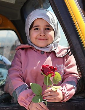 Smiling Syrian child holding a rose